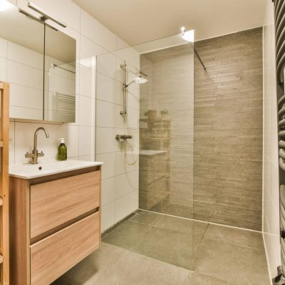 a bathroom with a shower, sink and towel rack on the wall next to it is a glass shower door